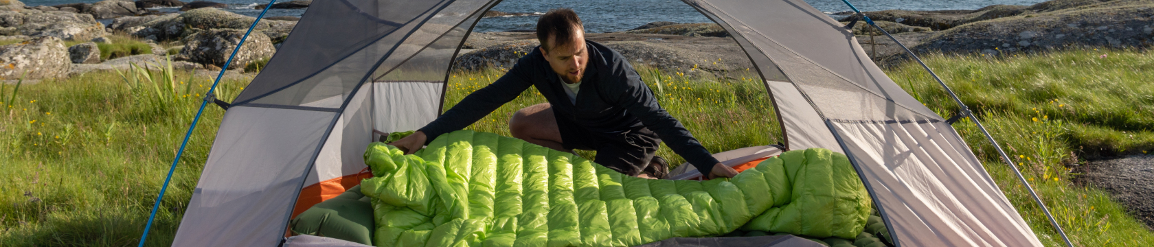 man legt zijn slaapzak klaar in de tent